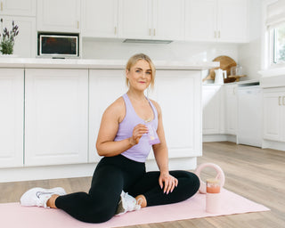 Lady on a yoga mat eating sneaky wholefood birthday cake better being protein bar post workout