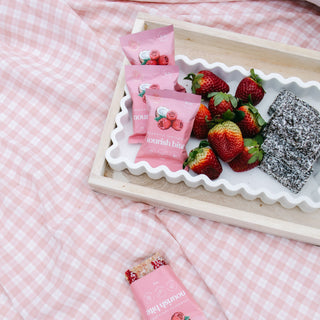 Sneaky Wholefoods Raspberry Lamington Nourish Bite displayed on a picnic platter with strawberries and lamingtons, offering a plant-based, high-protein, nutrient-rich snack for outdoor gatherings