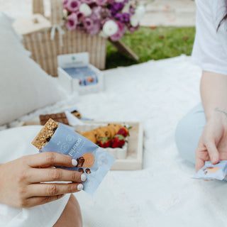 Woman enjoying a Sneaky Wholefoods Peanut Butter Cookie Nourish Bite, revealing the rich, wholefood-based texture inside this gluten-free, plant-based, high-protein snack