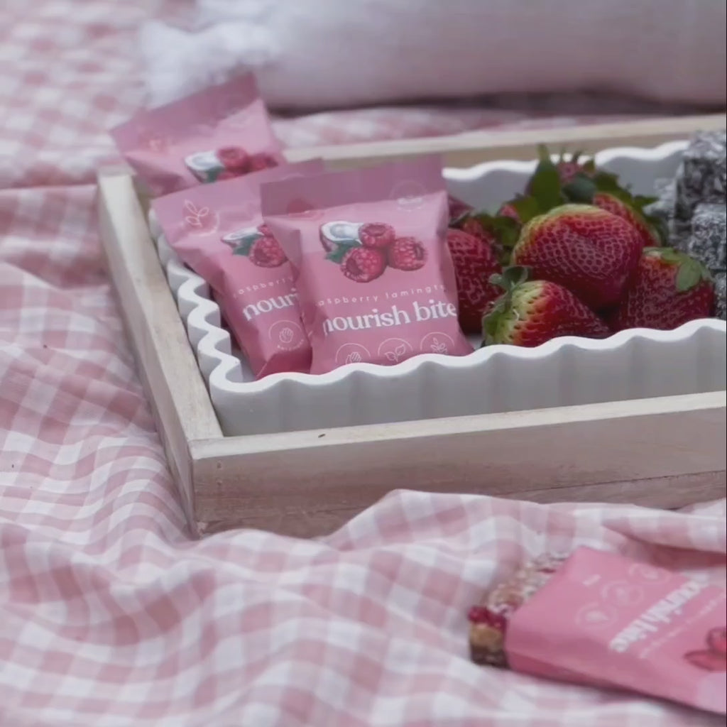 Video of friends enjoying a relaxed picnic while connecting and snacking on Sneaky Wholefoods Raspberry Lamington Nourish Bites, a plant-based, gluten-free, nutrient-rich snack perfect for a healthy lifestyle.