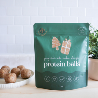 eaky Wholefoods Gingerbread Cookie Dough Protein Balls with the packet, highlighting a holiday-perfect snack that pairs well with a Christmas-themed drink for a wholesome, high-protein treat.