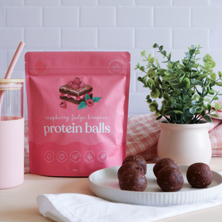 Raspberry Fudge Brownie Protein Balls, packet, and smoothie cup, highlighting a nutritious, high-protein snack option that’s plant-based and gluten-free, perfect for pairing with a healthy smoothie