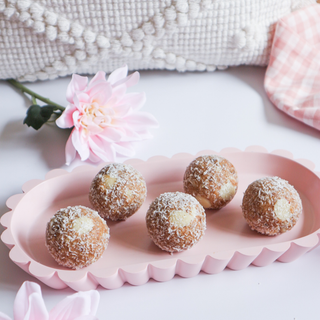 A pink ceramic platter showcasing neatly arranged protein balls, complemented by a light and airy background for a playful touch.