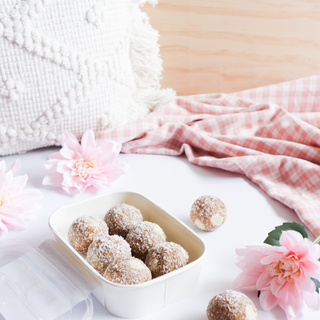 An open packet of protein balls spilling onto out, surrounded light airy vibe with flowers 